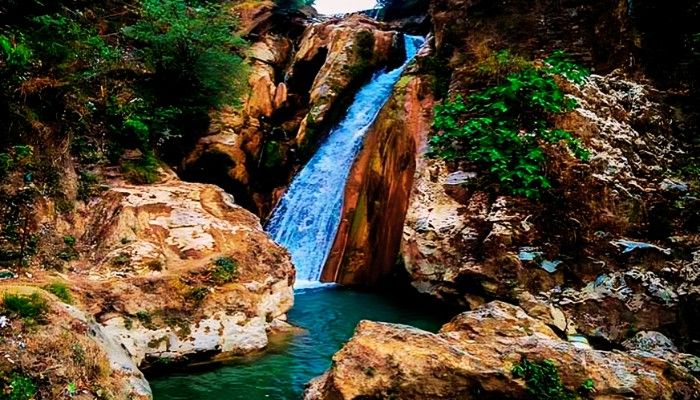 Bhatta Falls waterfall near Mussoorie surrounded by rocky cliffs and natural greenery