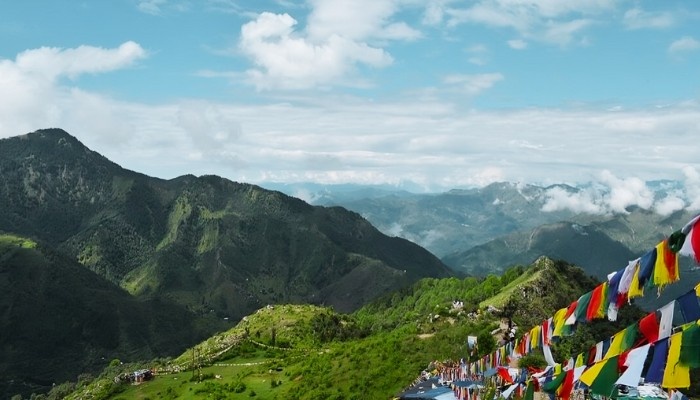 Beautiful landscape of Happy Valley in Mussoorie featuring green meadows, forested slopes, and serene mountain views.
