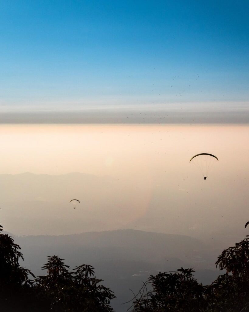 Panoramic view of Bir Billing with paragliders in the sky, lush green hills, and serene landscapes, ideal for adventure enthusiasts