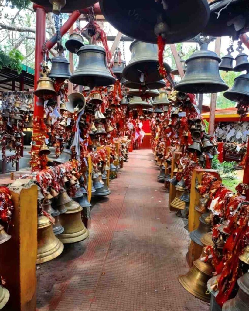 Chitai Golu Devta Temple near Almora with bells, prayer threads, and forest surroundings.